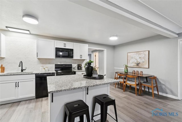 kitchen featuring black appliances, a kitchen bar, white cabinetry, and sink