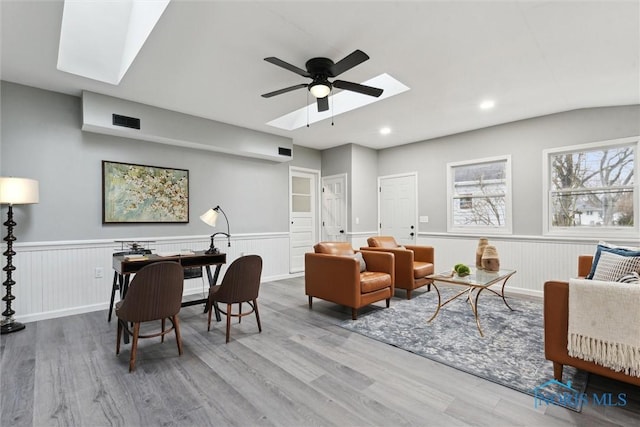 interior space featuring hardwood / wood-style floors, ceiling fan, and vaulted ceiling with skylight