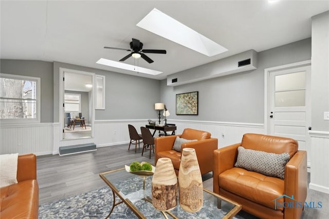 living room with dark hardwood / wood-style flooring, a skylight, and ceiling fan