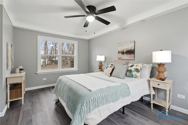 bedroom with dark hardwood / wood-style floors, a raised ceiling, and ceiling fan