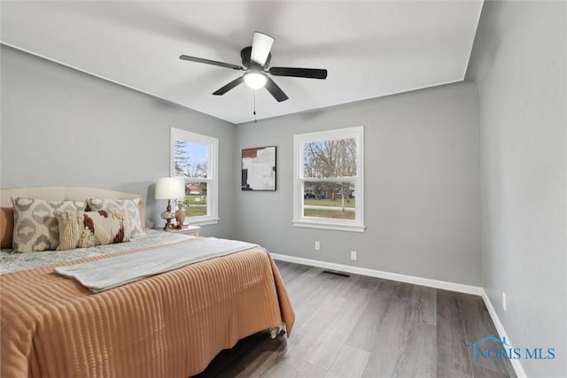 bedroom featuring multiple windows, ceiling fan, and dark hardwood / wood-style flooring