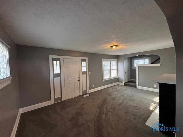 carpeted foyer with a textured ceiling