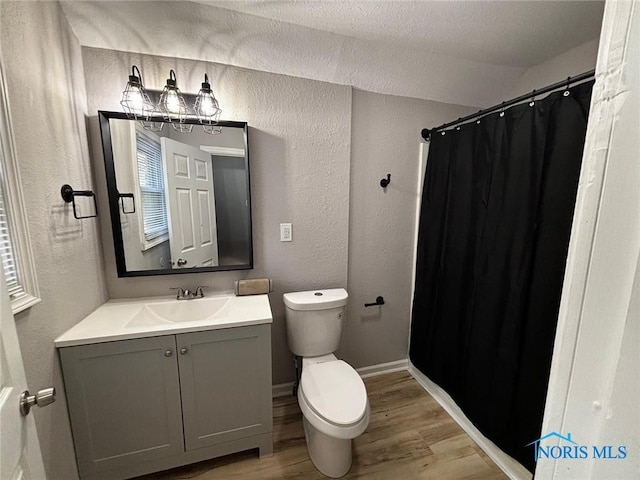 bathroom featuring wood-type flooring, a textured ceiling, toilet, vanity, and a shower with shower curtain