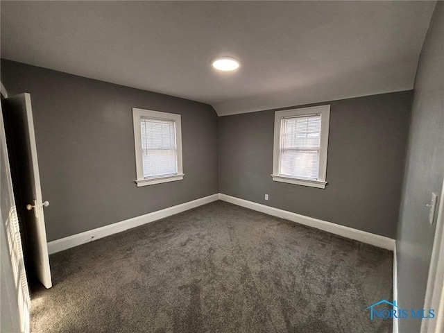 carpeted empty room with vaulted ceiling