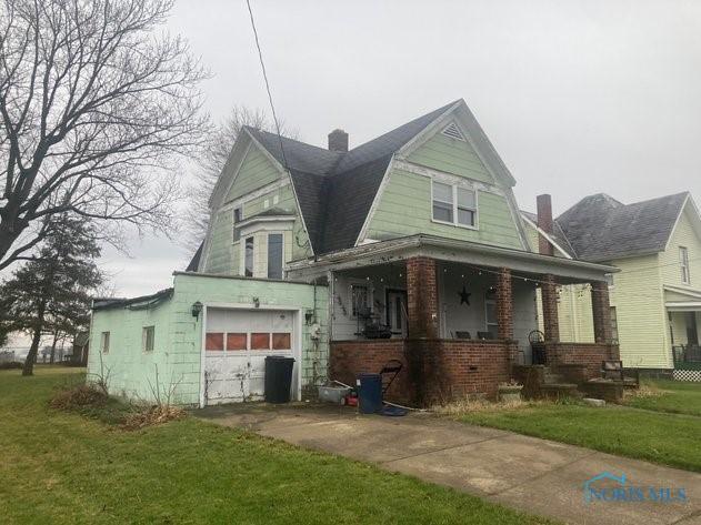 view of front facade with covered porch, a garage, and a front lawn