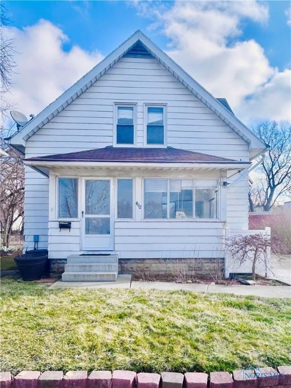 rear view of house featuring a sunroom and a lawn