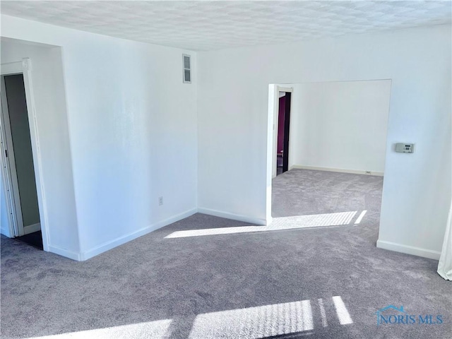 carpeted empty room with a textured ceiling