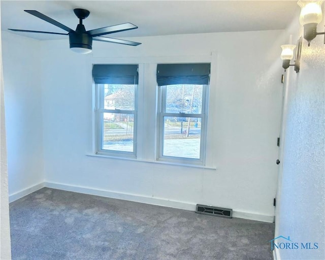 unfurnished room with ceiling fan and dark carpet