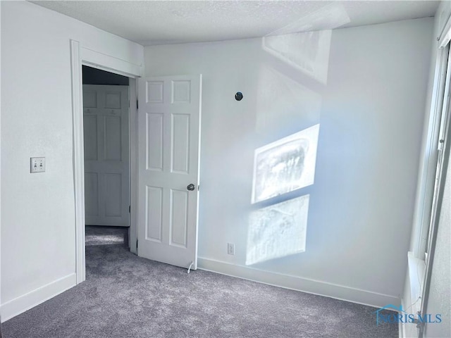 carpeted empty room with a textured ceiling