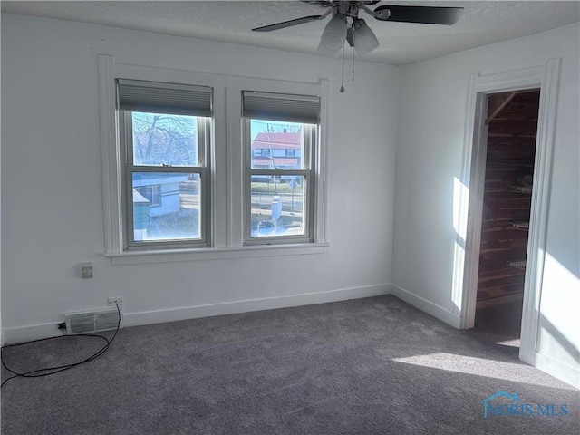 empty room featuring ceiling fan and dark carpet