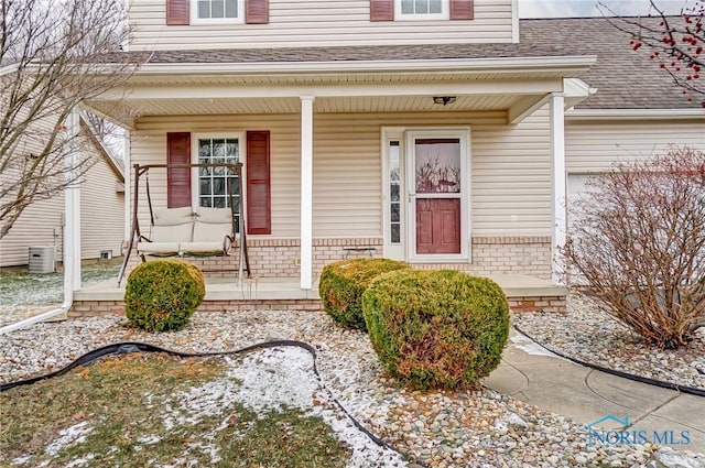 view of exterior entry with covered porch and central air condition unit