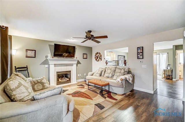 living room with a fireplace, hardwood / wood-style flooring, ceiling fan, and a healthy amount of sunlight