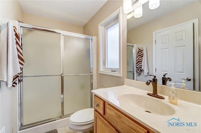 bathroom featuring vanity, a shower with shower door, and toilet