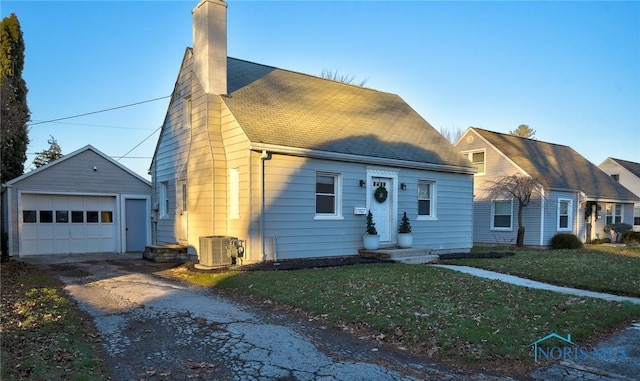 view of front of house with a front yard, an outbuilding, central AC unit, and a garage