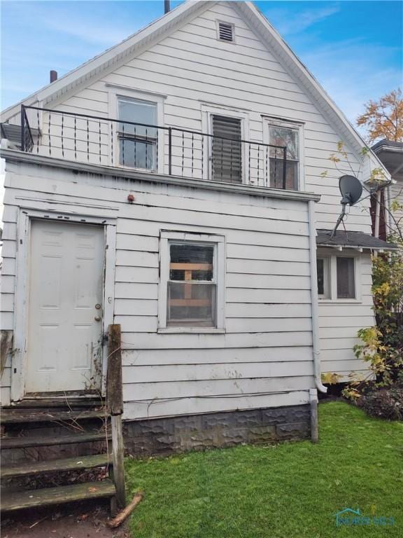 rear view of house with a yard and a balcony