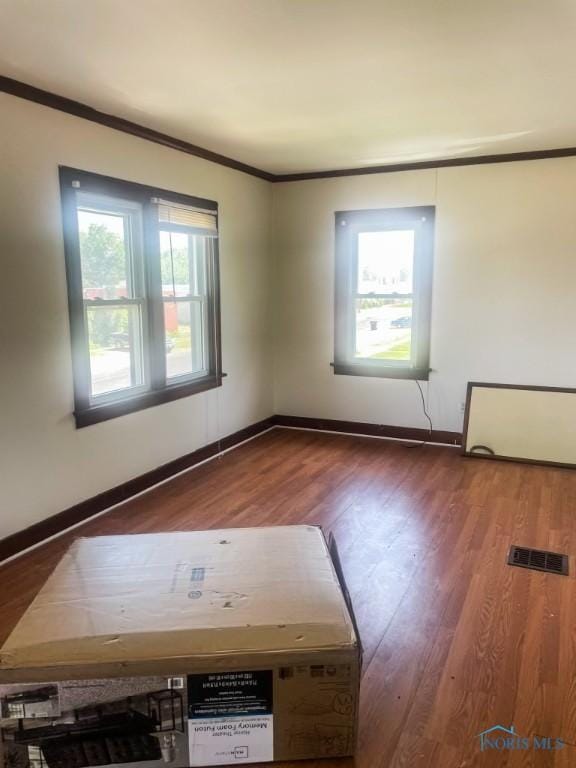 spare room featuring hardwood / wood-style floors and crown molding