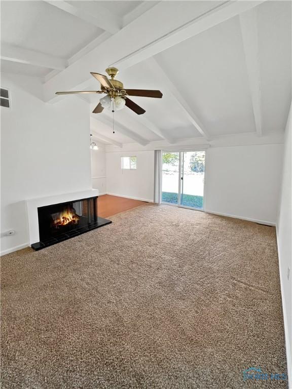 unfurnished living room with carpet, ceiling fan, and lofted ceiling with beams