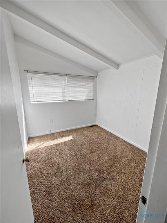 spare room with beam ceiling and carpet floors