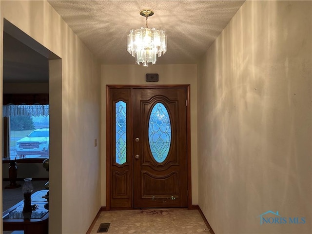 foyer entrance featuring a notable chandelier and a textured ceiling