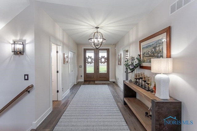 entryway with french doors, an inviting chandelier, and dark wood-type flooring