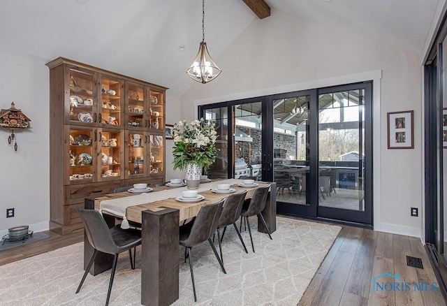 dining space featuring beam ceiling, french doors, high vaulted ceiling, a chandelier, and light wood-type flooring