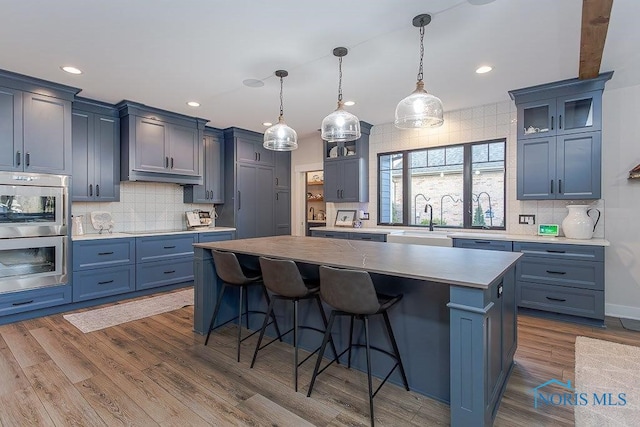 kitchen with wood-type flooring, a kitchen island, blue cabinets, and a breakfast bar area