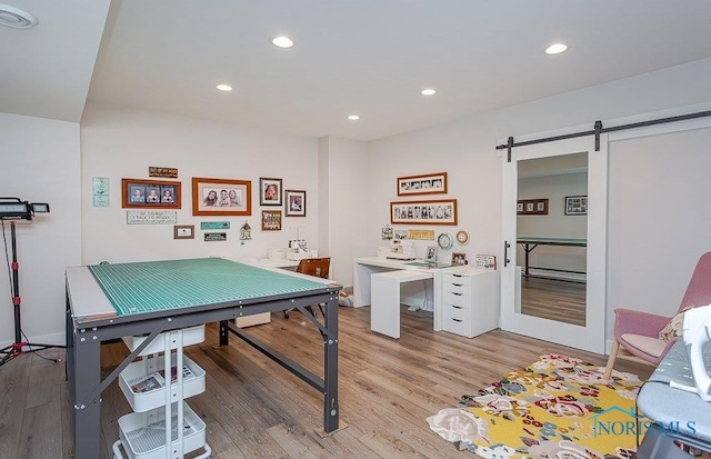 recreation room with a barn door and light hardwood / wood-style floors