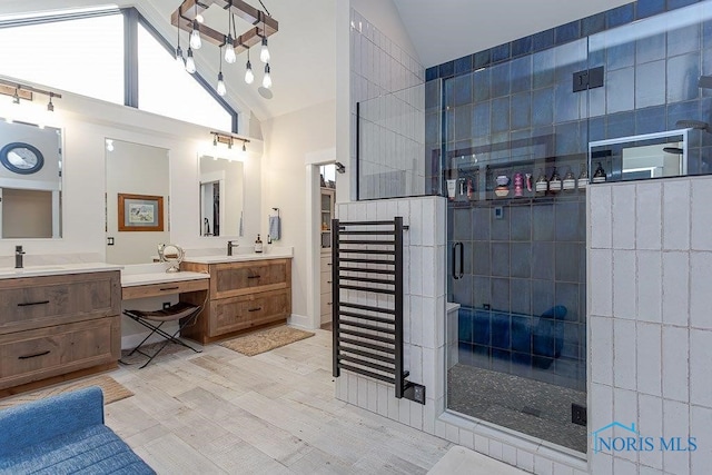 bathroom featuring hardwood / wood-style flooring, vanity, a shower with shower door, and high vaulted ceiling