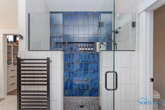 bathroom featuring a shower with shower door and toilet