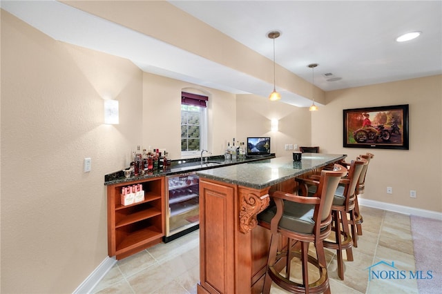 bar with pendant lighting, sink, dark stone countertops, light tile patterned floors, and beverage cooler