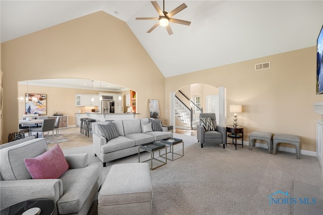 carpeted living room with ceiling fan and high vaulted ceiling