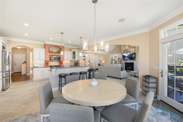 dining area with ornamental molding, sink, and a chandelier