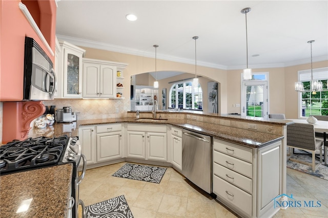 kitchen with dark stone counters, white cabinets, sink, decorative light fixtures, and stainless steel appliances