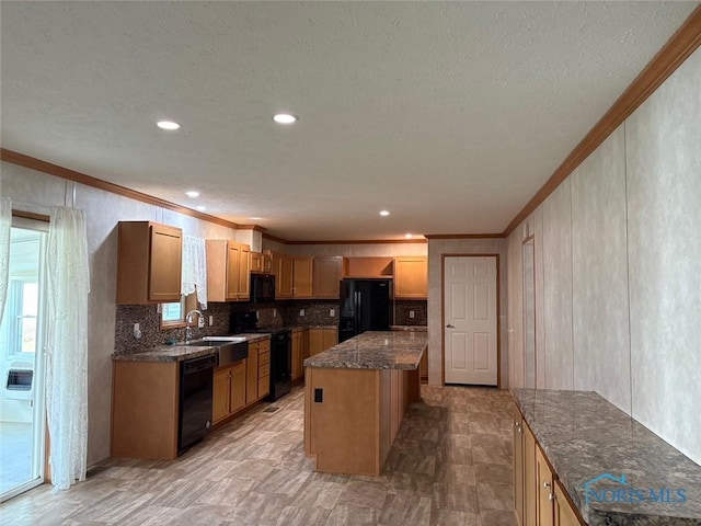 kitchen with dark stone counters, crown molding, sink, black appliances, and a center island