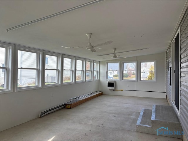 unfurnished sunroom with heating unit and ceiling fan