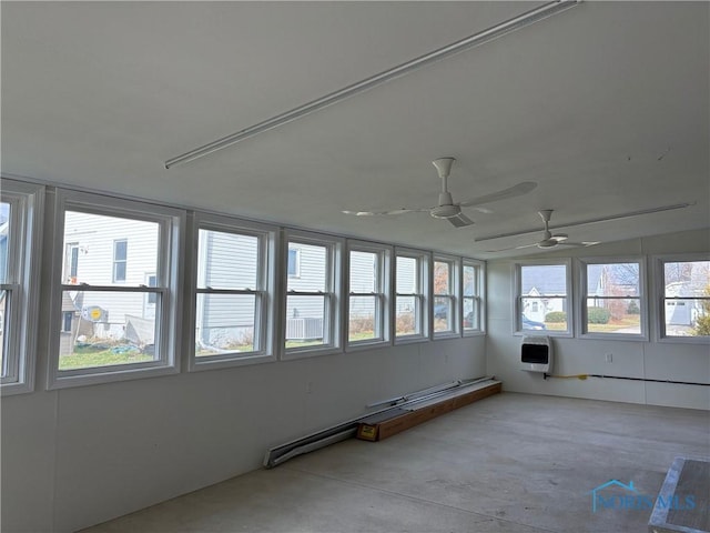 unfurnished sunroom with ceiling fan and heating unit