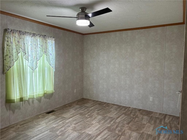 empty room with ceiling fan, ornamental molding, and a textured ceiling