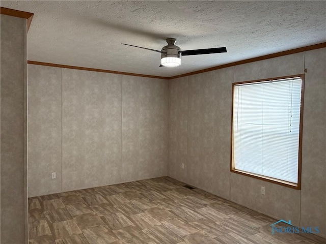 empty room featuring ceiling fan, crown molding, and a textured ceiling