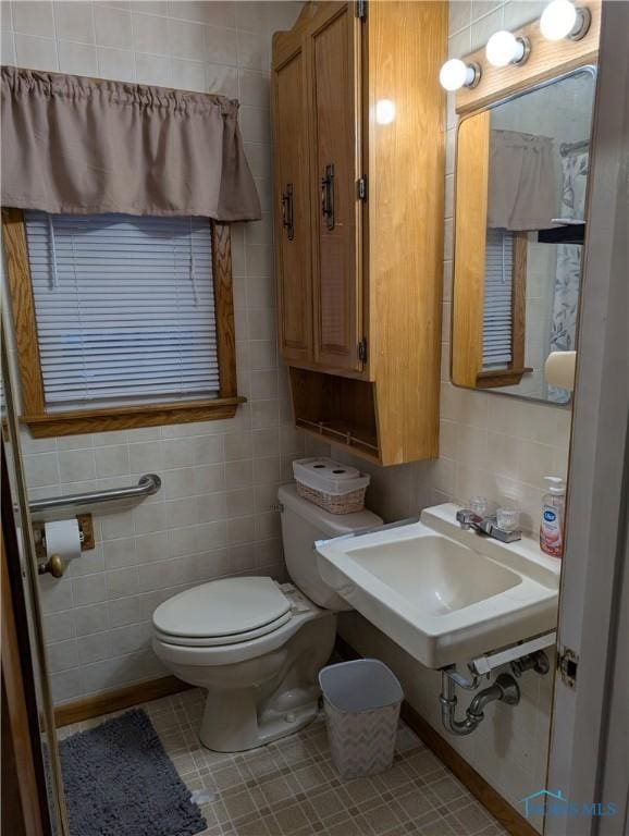 bathroom with sink, tile patterned flooring, tile walls, and toilet