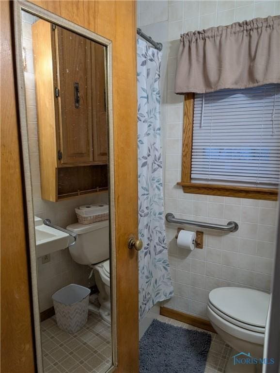 bathroom with tile patterned floors, walk in shower, tile walls, and toilet