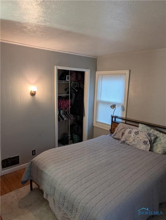 bedroom with hardwood / wood-style flooring, a textured ceiling, and a closet