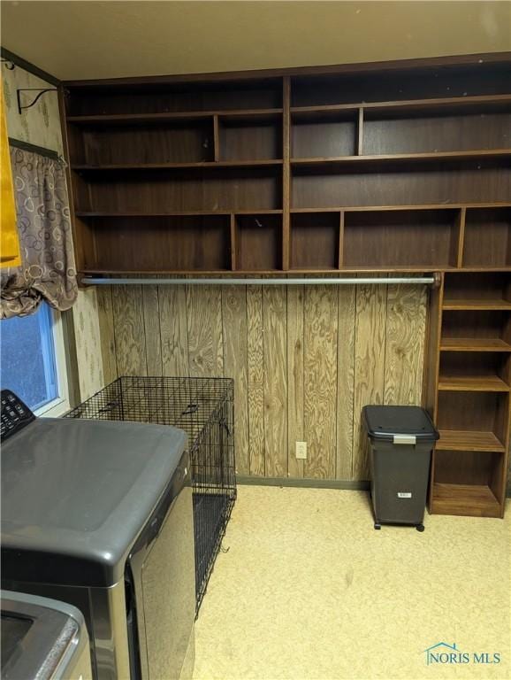 interior space featuring carpet, wooden walls, and washing machine and clothes dryer