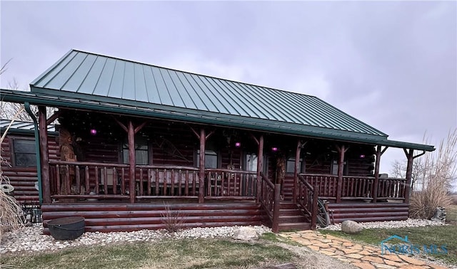 view of front of home with covered porch, metal roof, a standing seam roof, and log siding