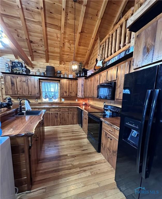 kitchen with light wood-type flooring, black appliances, wooden ceiling, and a sink