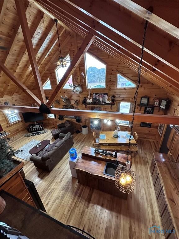 living room with vaulted ceiling with beams, hardwood / wood-style floors, wood walls, and wooden ceiling