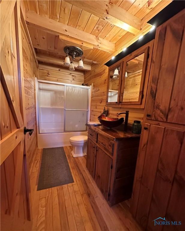 bathroom featuring toilet, wood walls, wooden ceiling, beamed ceiling, and hardwood / wood-style flooring