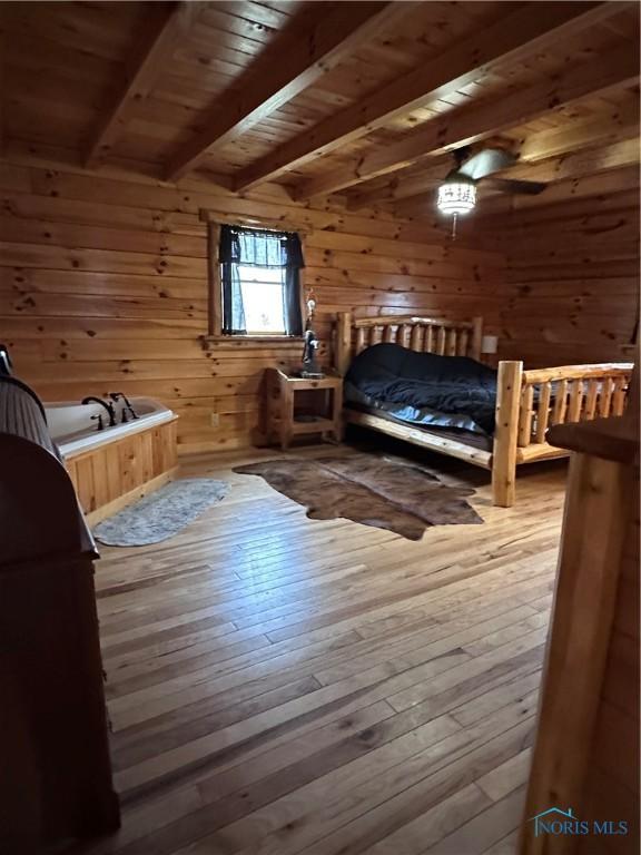 bedroom with wood walls, beamed ceiling, wood ceiling, and hardwood / wood-style flooring