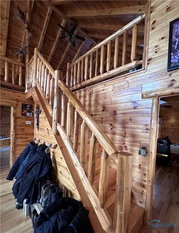 stairway with wood-type flooring, high vaulted ceiling, wood walls, and wooden ceiling