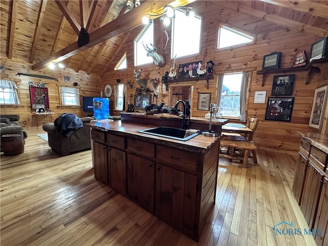 kitchen with light wood-style floors, open floor plan, a sink, and wooden walls