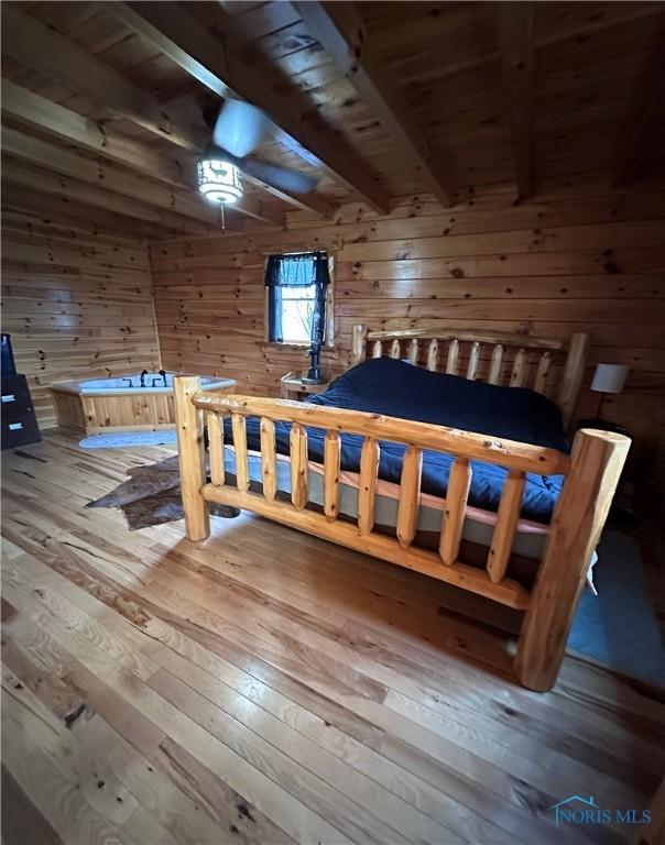 bedroom with beamed ceiling, wood walls, wooden ceiling, and hardwood / wood-style flooring